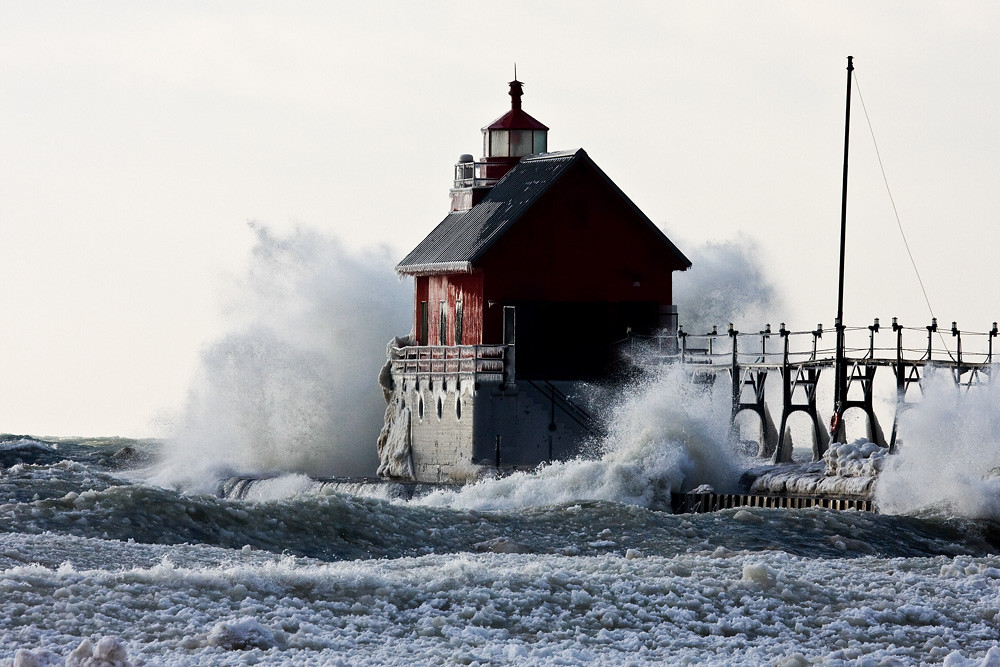 Who Defends the Great Lakes? Image of waves crashing against Lighthouse in Lake Michigan.